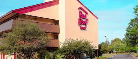 A Red Roof Inn with a two-story structure, a red roof, and a sign on the side.