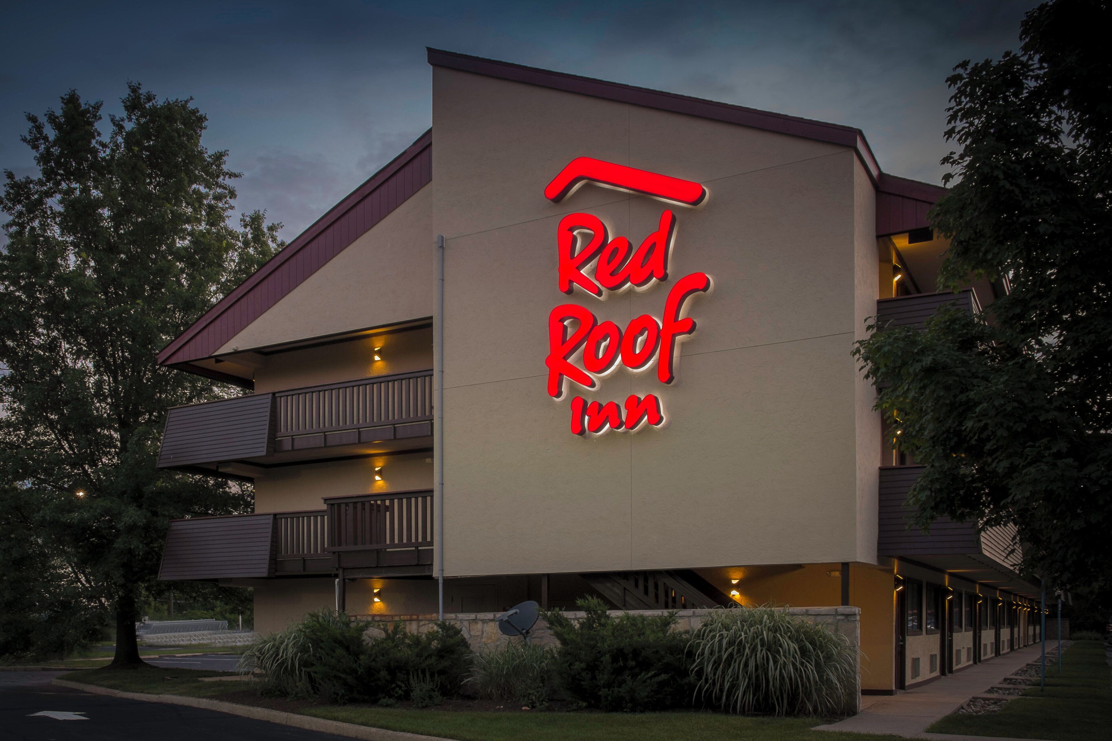 Edifício Red Roof Inn com uma placa iluminada em destaque, várias varandas e uma entrada bem iluminada.
