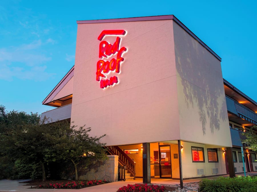 A hotel with a prominent neon sign, a visible entrance, and a staircase leading to the lobby.