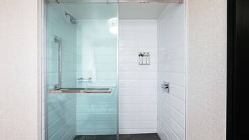 A modern shower with glass doors, a glass shower bench, and a wall-mounted towel rack.