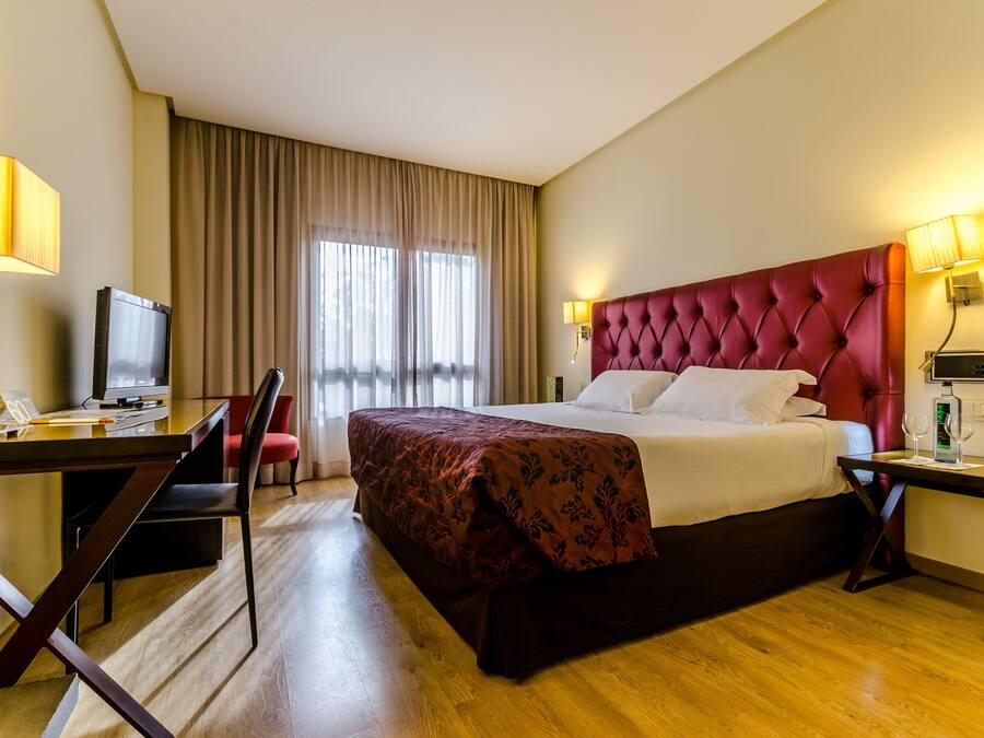 A hotel room with a large bed, a desk with a computer, a chair, and a television.