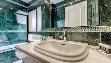 A modern bathroom with a large sink, a mirror, and a shower area.