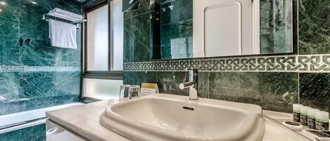 A modern bathroom with a large sink, a mirror, and a shower area.