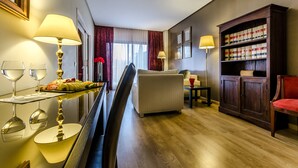 A hotel room with a dining area, a sofa, a bookshelf, and a mirror. - Hotel Exe Guadalete (Jerez de la Frontera)