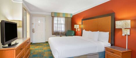 A hotel room with a bed, a television on a dresser, a chair, and a nightstand.