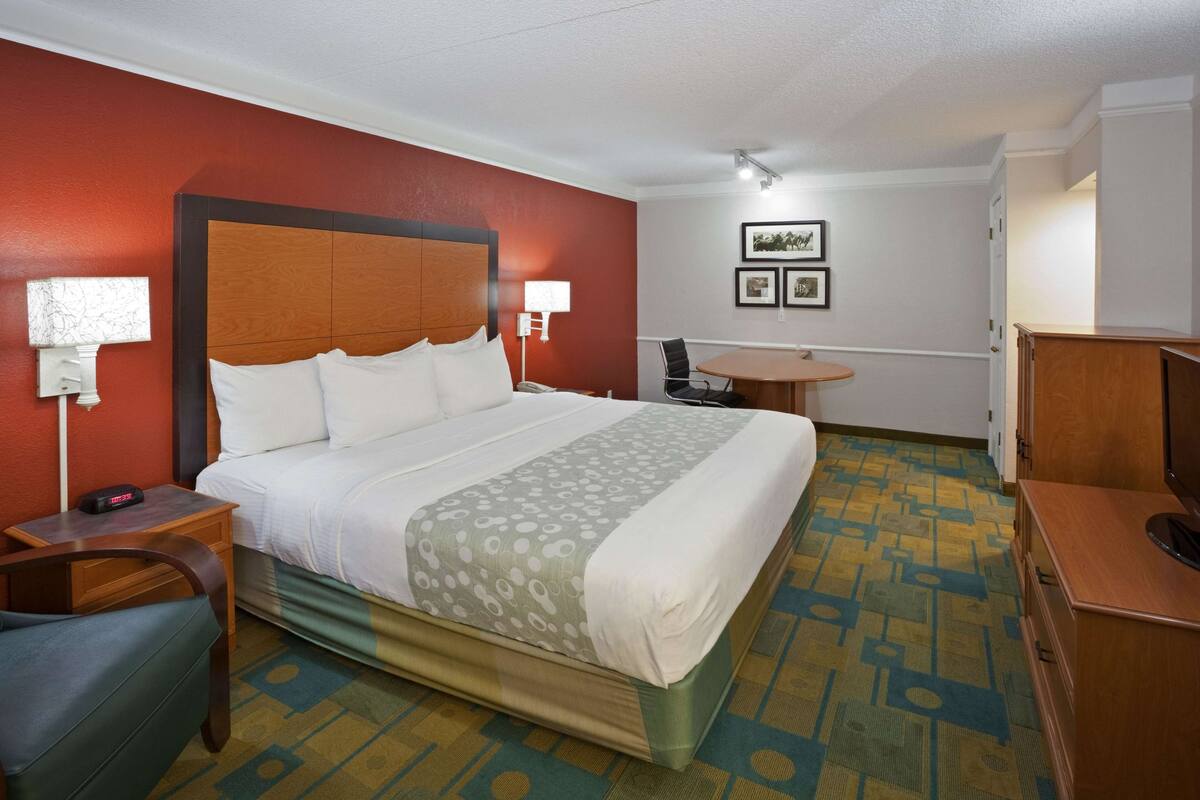 Een hotelkamer met een groot bed, een bureau, een stoel, een kleine tafel en een televisie.