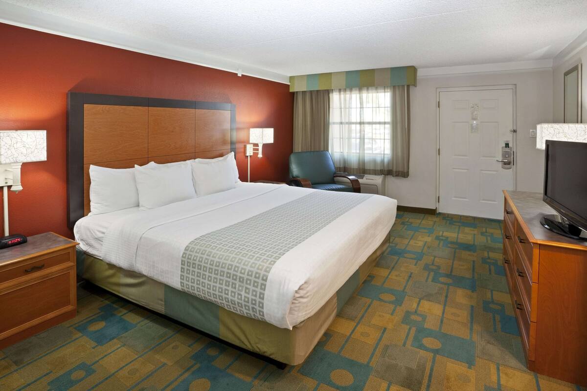 Een hotelkamer met een groot bed, een televisie, een bureau en een stoel.