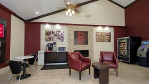 A Red Roof Inn lobby with a reception desk, seating area, and a vending machine. - Red Roof Inn New Orleans - Westbank (Harvey)