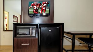 A compact kitchenette with a microwave, refrigerator, and a television mounted above it. - Red Roof Inn New Orleans - Westbank (Harvey)