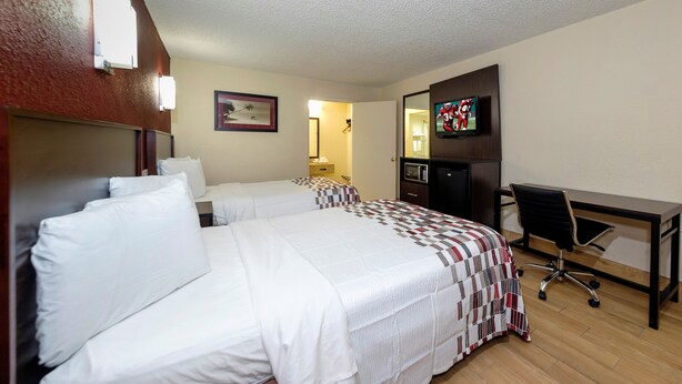 A hotel room with two beds, a desk, a television, and a microwave. - Red Roof Inn New Orleans - Westbank (Harvey)