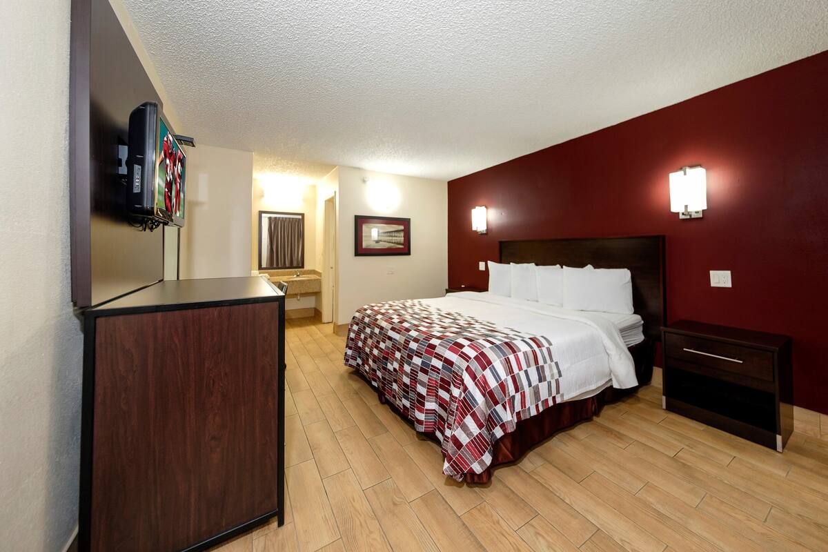 A hotel room with a bed, a TV, a bedside table, and a nightstand.