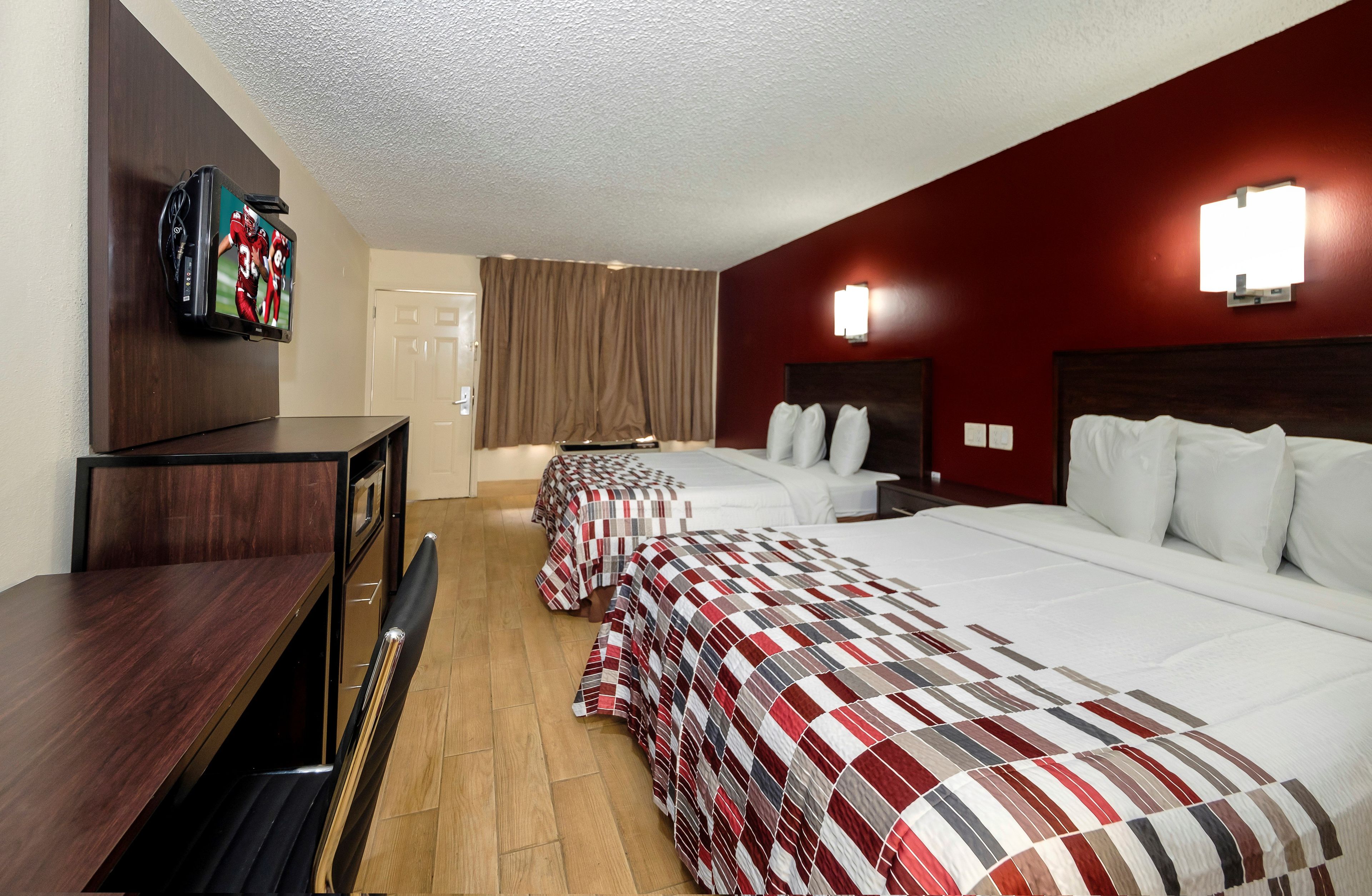 Habitación de hotel con dos camas, televisión, escritorio y armario.