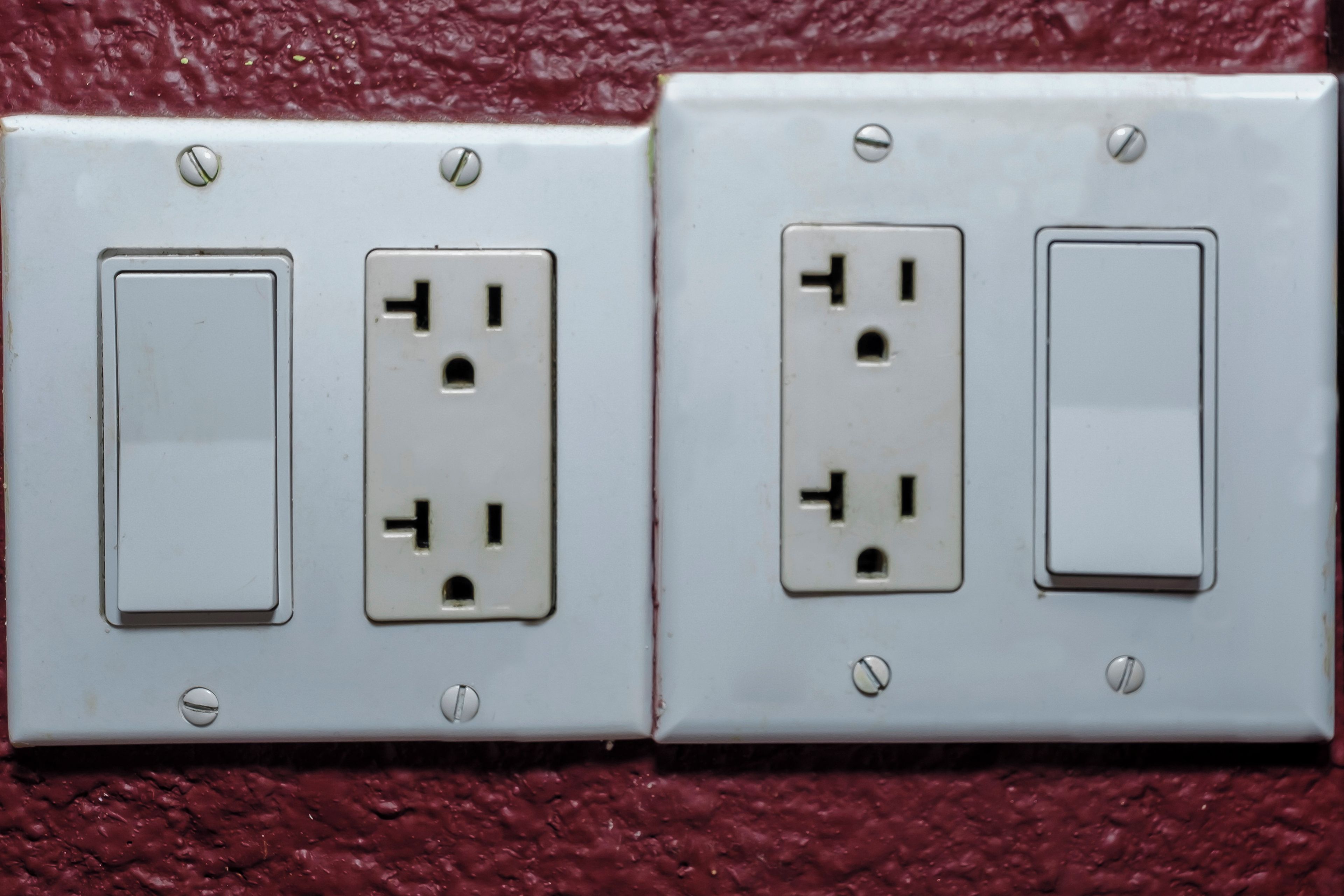 Toma de corriente empotrada en la pared con dos interruptores y un enchufe.