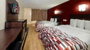 Habitación de hotel con dos camas, televisión, escritorio y armario.
