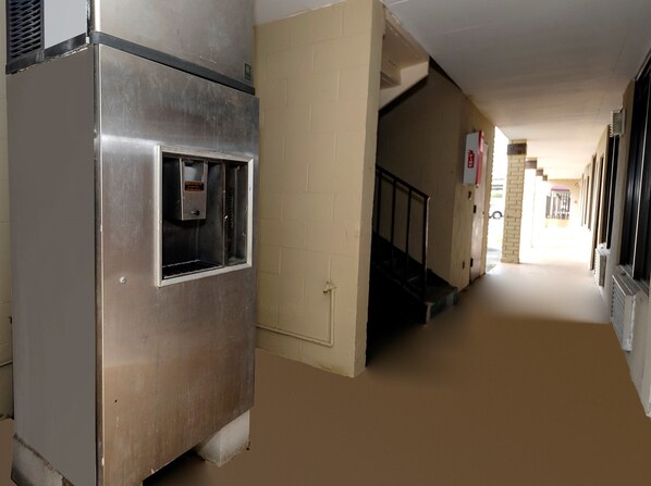 A corridor with a vending machine, a staircase, and a door leading to another room. - Red Roof Inn New Orleans - Westbank (Harvey)