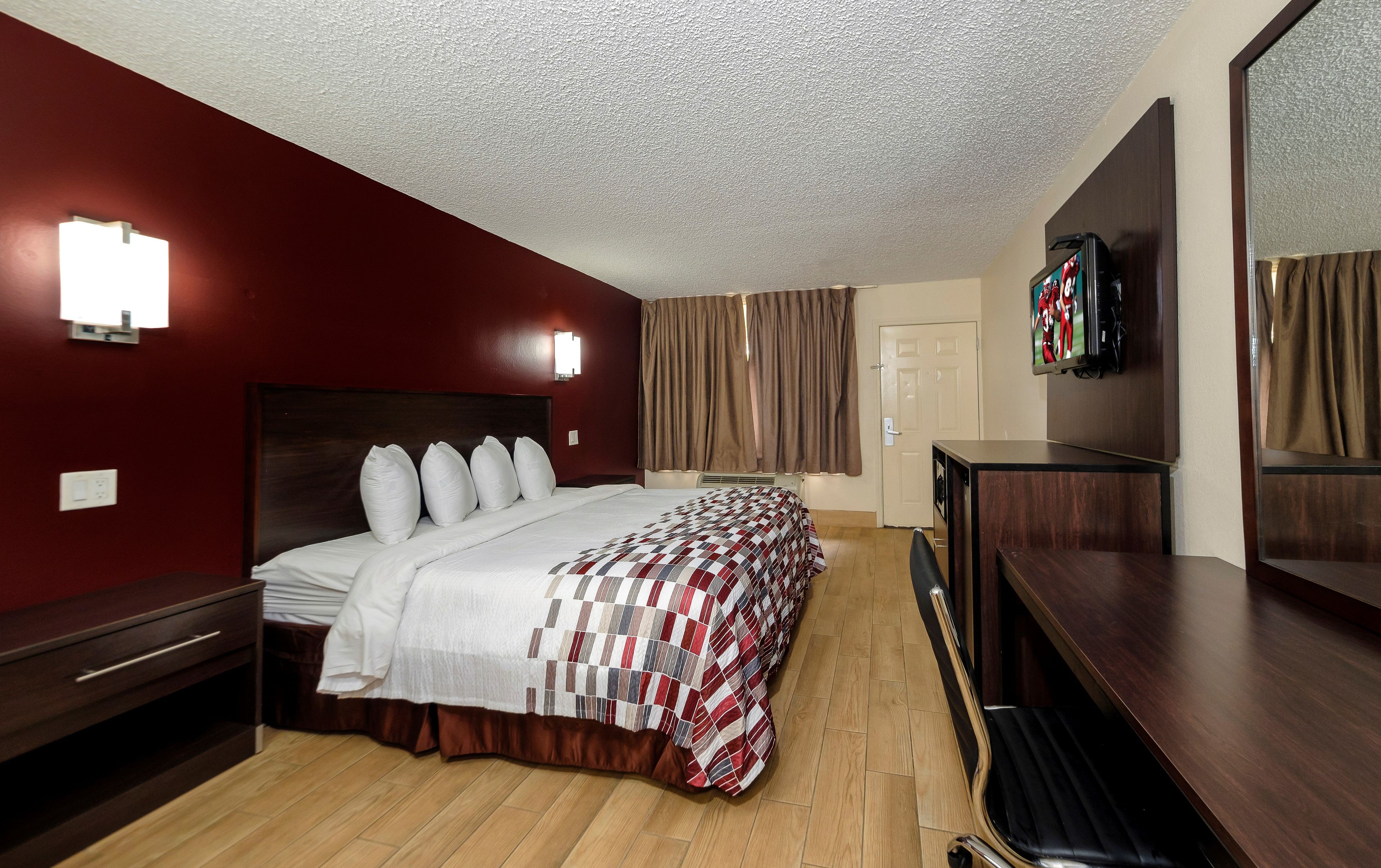 A hotel room with a bed, a TV, a desk, and a mirror.