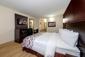 A hotel room with a bed, a desk, a television, a mirror, and a picture on the wall. - Red Roof Inn New Orleans - Westbank (Harvey)