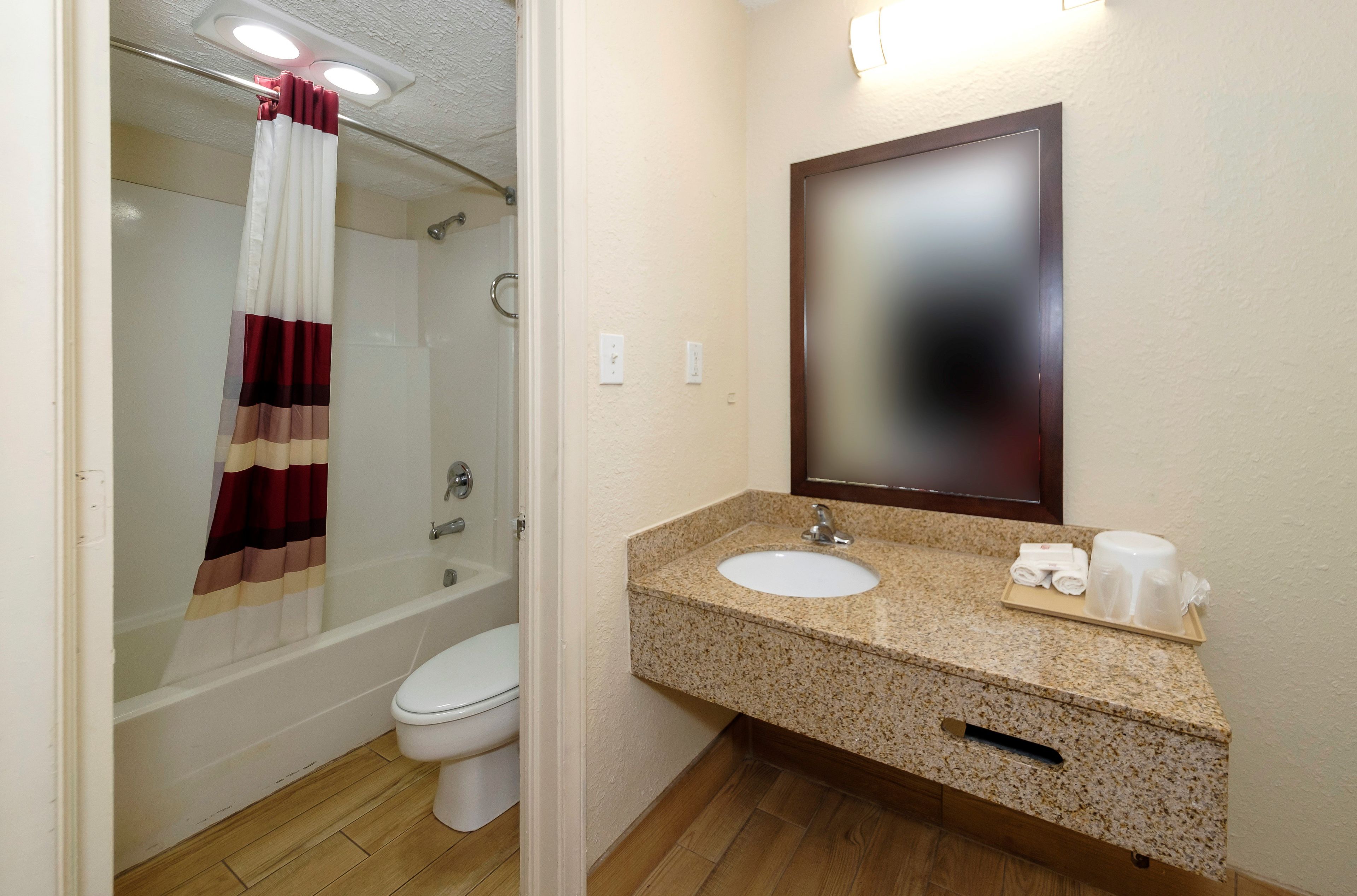 A bathroom with a shower, toilet, sink, and mirror.