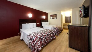 Habitación de hotel con dos camas, televisión y escritorio.