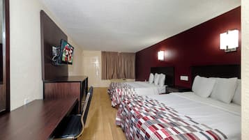 A hotel room with two beds, a desk, a chair, a television, and a bathroom door.