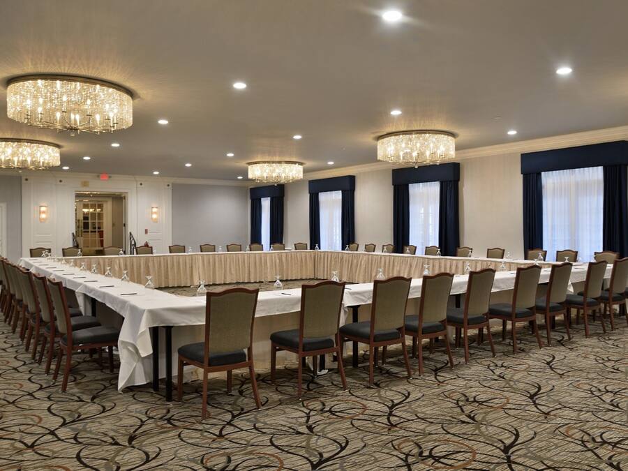 A conference room with a long table, chairs, chandeliers, and a carpeted floor.