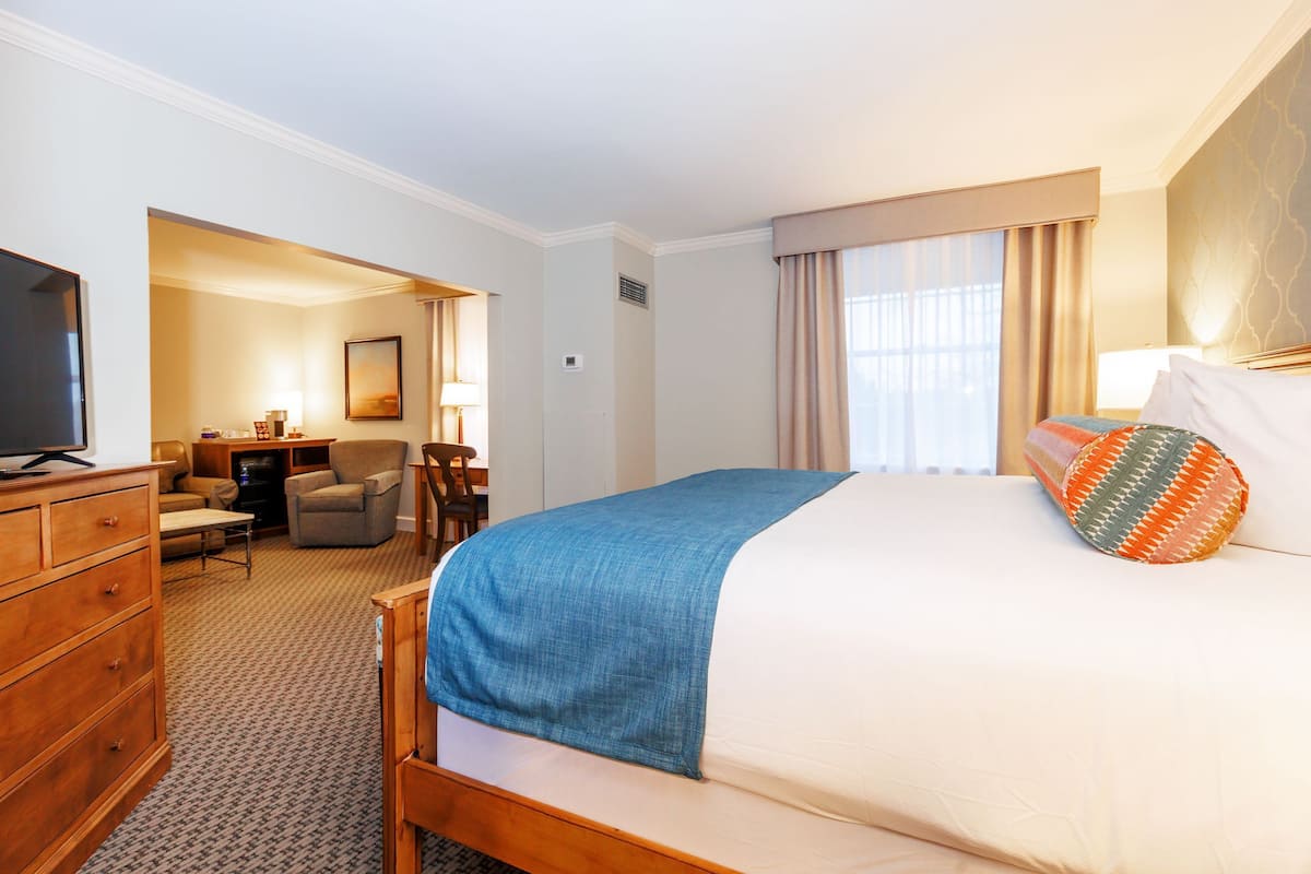 A hotel room with a bed, a TV, a desk, and a chair.
