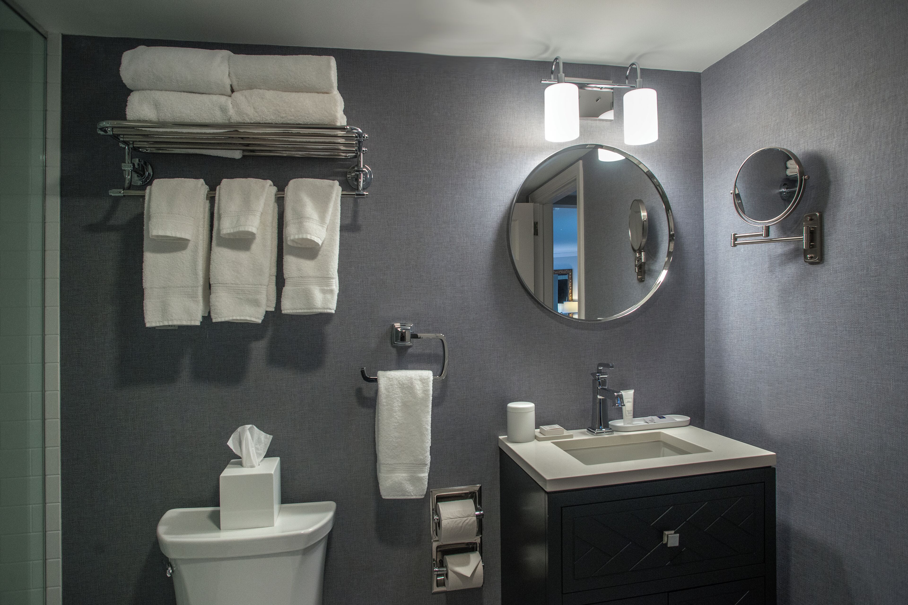 A bathroom with a toilet, sink, mirror, towel rack, and a view of the sky.