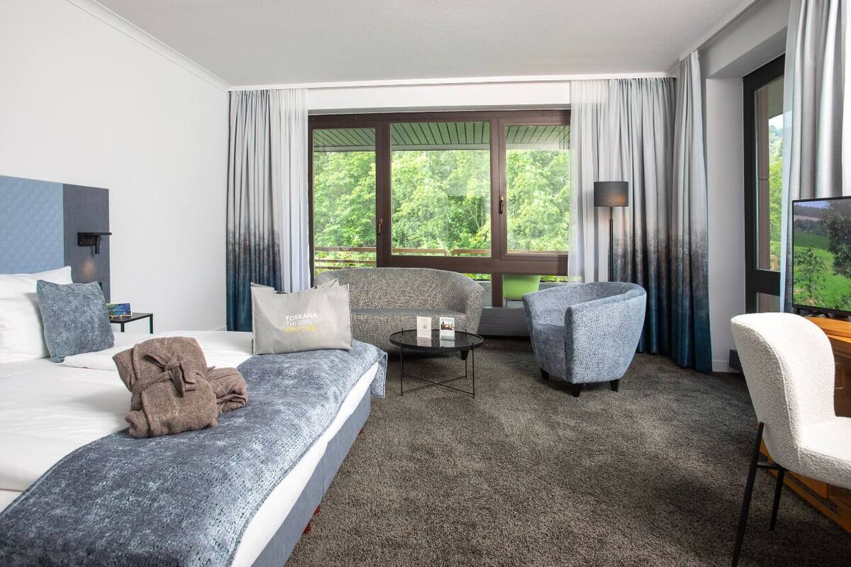 A hotel room with a bed, two armchairs, a coffee table, and a TV.