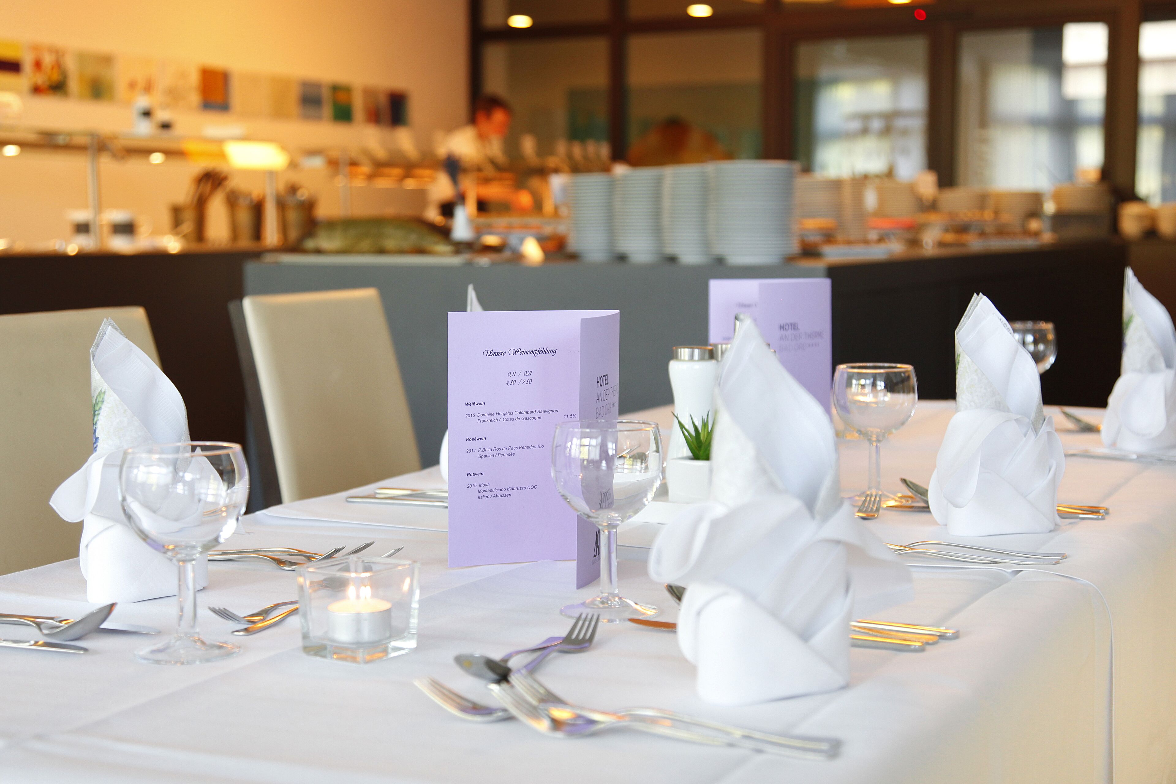 A table set for a meal with a menu, candles, and white napkins.