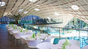 A spacious indoor area with a high, geometric ceiling and a glass railing overlooking a pool. - Hotel an der Therme Bad Orb (Bad Orb)