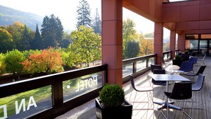 A terrace with outdoor seating, a view of trees and mountains, and a sign reading "HOTEL". - Hotel an der Therme Bad Orb (Bad Orb)