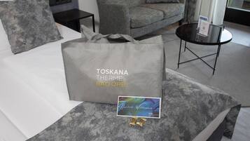 Una habitación de hotel con cama, sofá de tela gris con estampado, una pequeña mesa redonda y un sillón tapizado gris.
