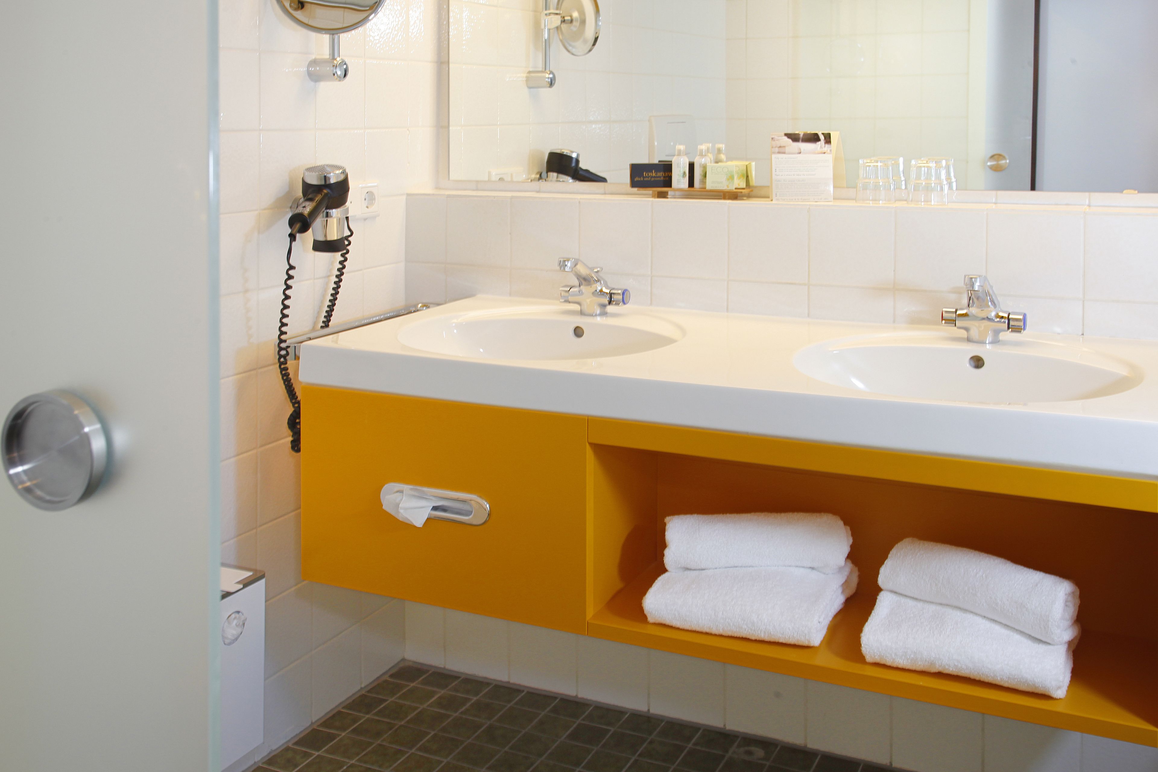 A bathroom with two sinks, a mirror, and a towel rack.