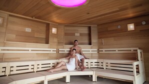 A sauna with wooden benches and a central pink light. - Hotel an der Therme Bad Orb (Bad Orb)