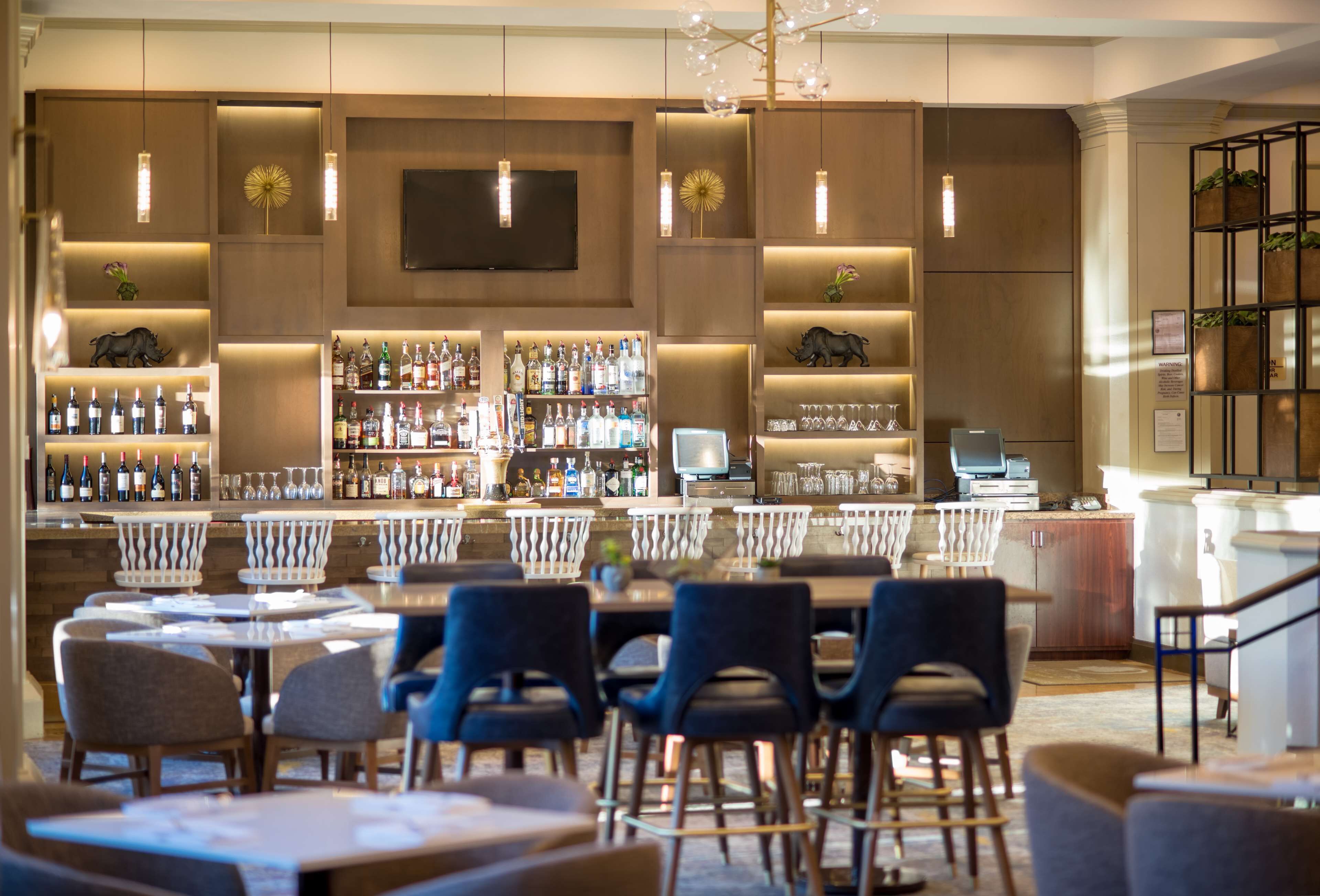 A bar area with multiple seating options and a variety of liquor bottles.