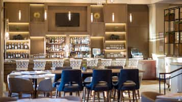 Uma área de bar com diversas opções de assento e uma variedade de garrafas de bebidas alcoólicas.