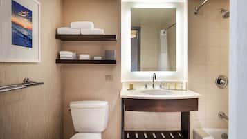A modern bathroom with a toilet, a sink with a mirror, a shower, and a towel rack with towels.