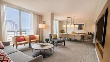 Een moderne hotelkamer met een zithoek, eethoek en een grote televisie.