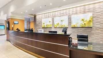 A hotel reception desk with a modern design, a digital screen, and a key drop box.