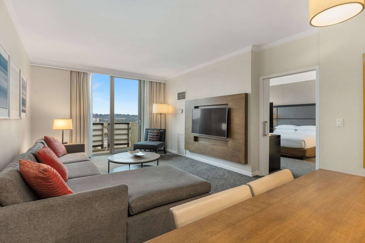 Una habitación de hotel moderna con sofá, mesa de centro, televisor y cama.