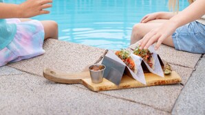 Un espace aménagé au bord de la piscine, avec une piscine en béton, des chaises longues et une terrasse en bois.