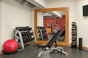 Un gimnasio con equipamiento de ejercicio, un espejo y una pelota de gimnasia roja.