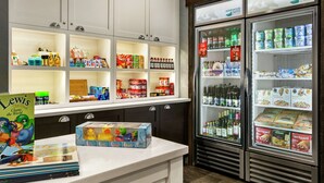 A hotel kitchenette with a variety of food items, a refrigerator stocked with beverages, and a children's toy set on the counter. - Homewood Suites by Hilton Syracuse/Liverpool (Liverpool)