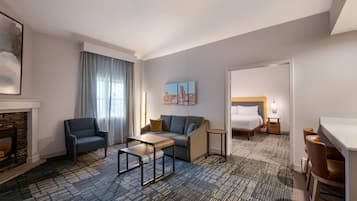 Et hotelværelse med sofa, lænestol, lille bord og en seng med et natbord.