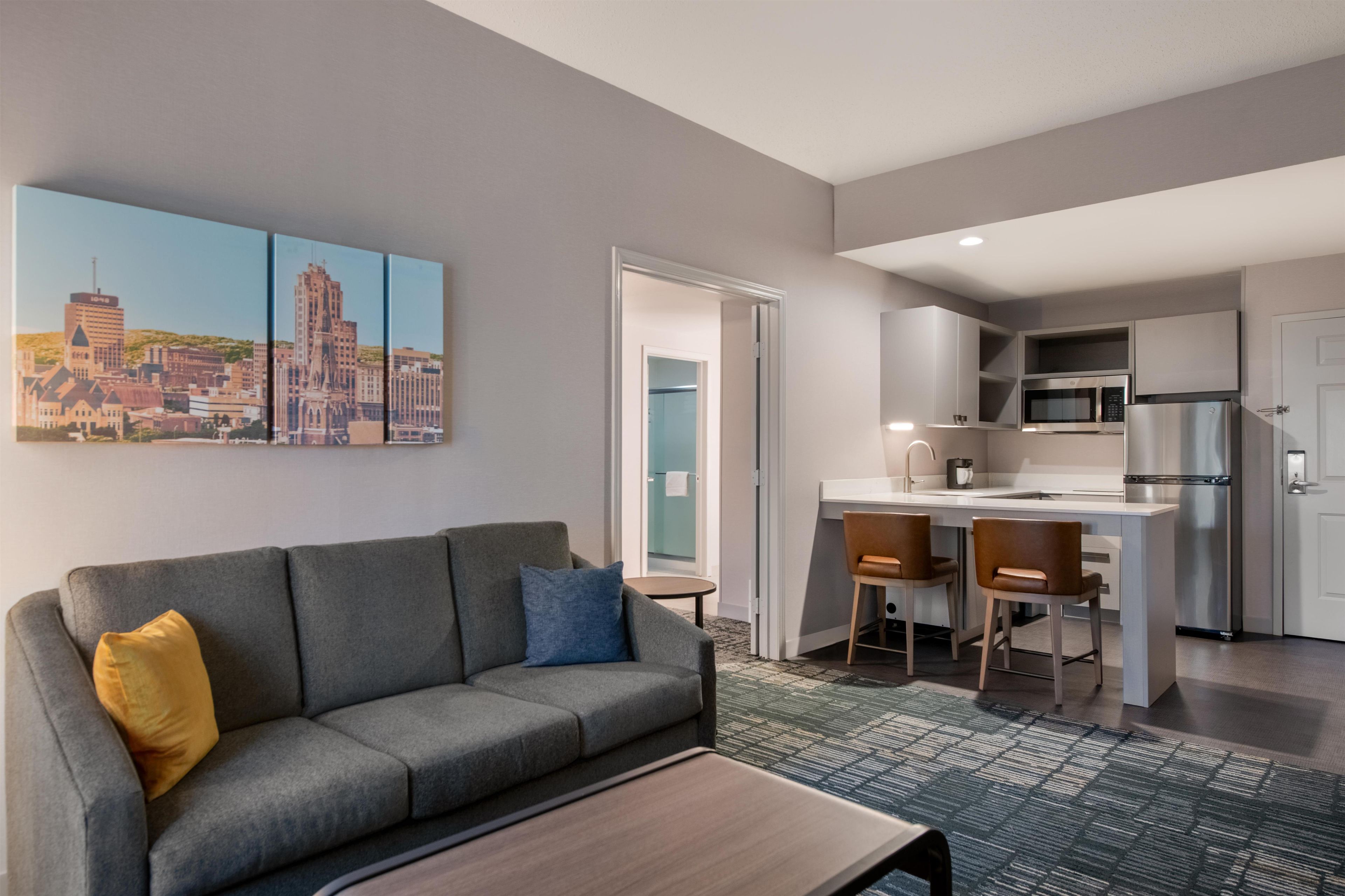 A modern living room with a gray sofa, a coffee table, and a cityscape painting on the wall.