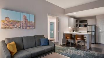 A modern living room with a gray sofa, a coffee table, and a cityscape painting on the wall.