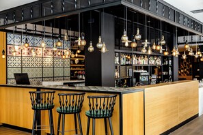 A modern bar area with hanging light fixtures, bar stools, and a tiled backsplash. - Motel One Madrid-Plaza de España (Madrid)