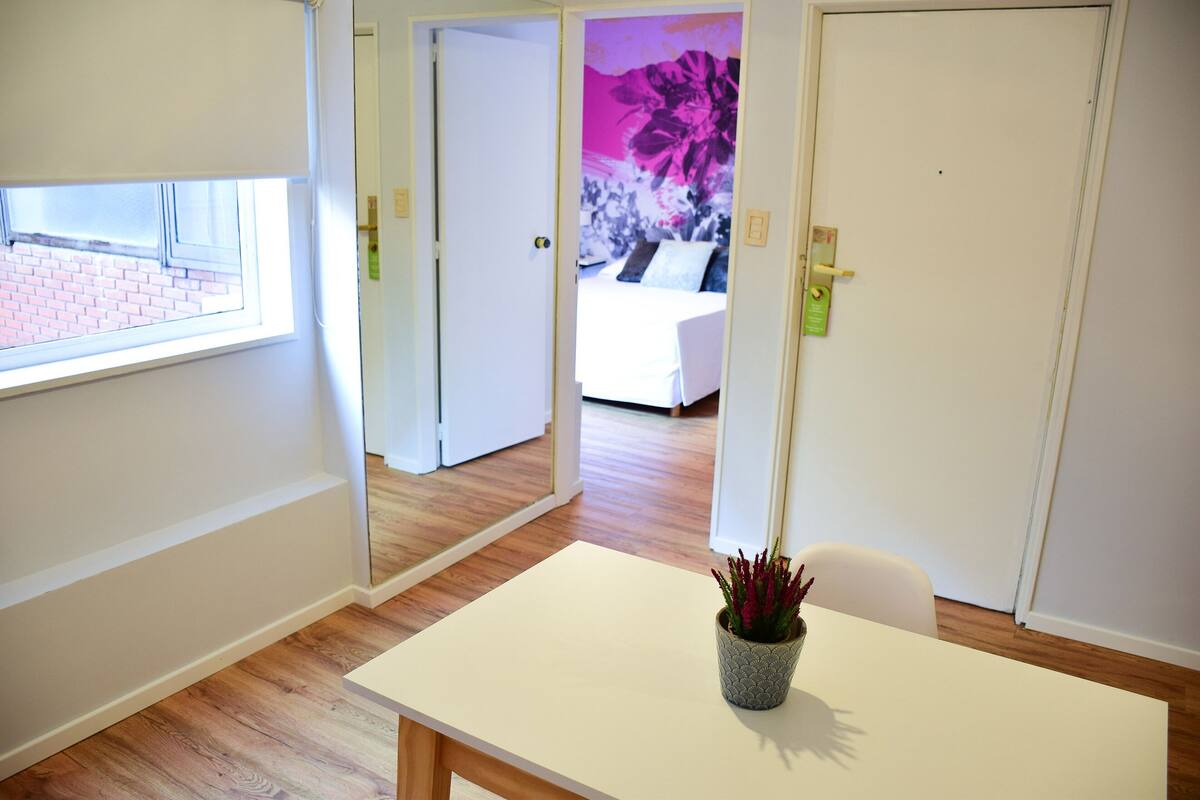 A room with a wooden floor, a white table, and a potted plant.