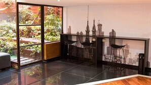 Ein modernes Zimmer mit großem Fenster, Stadtblick und einer kleinen Sitzecke mit Stühlen.