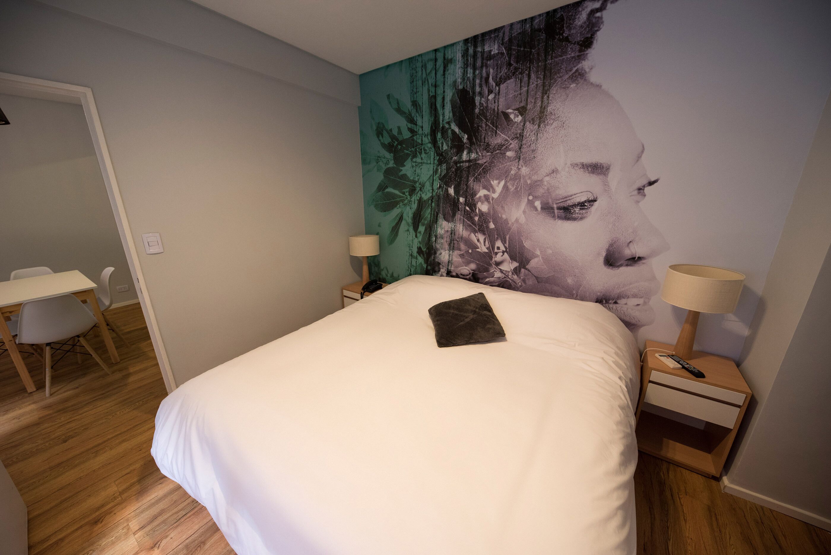 A bedroom with a bed, a desk, and a nightstand with lamps.
